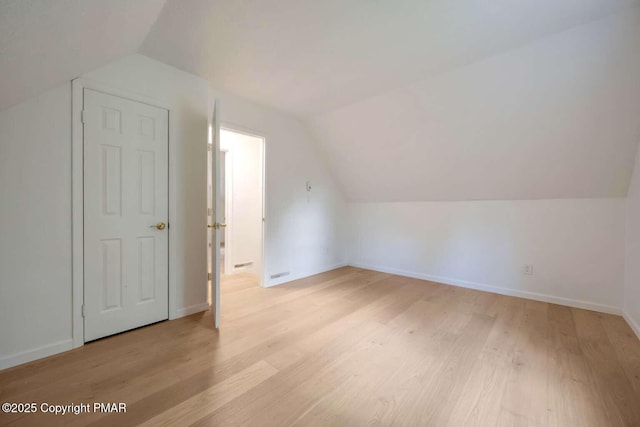 additional living space with vaulted ceiling and light wood-type flooring