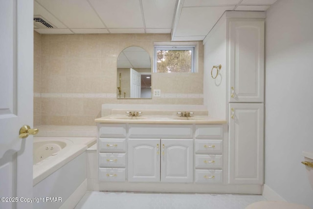 bathroom featuring a tub to relax in, vanity, and a drop ceiling