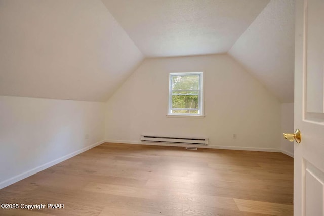 additional living space with baseboard heating, lofted ceiling, a textured ceiling, and light wood-type flooring