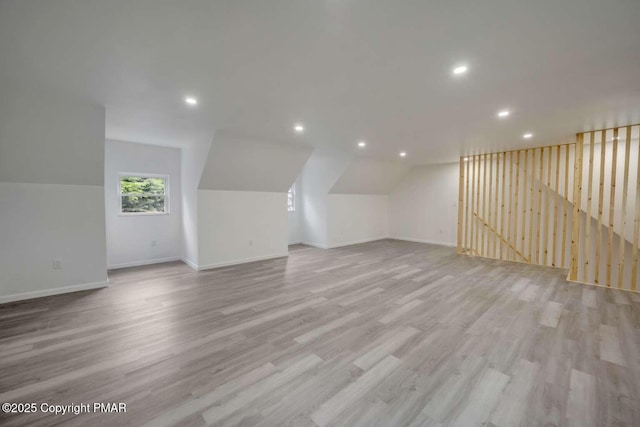 additional living space featuring light hardwood / wood-style flooring and vaulted ceiling