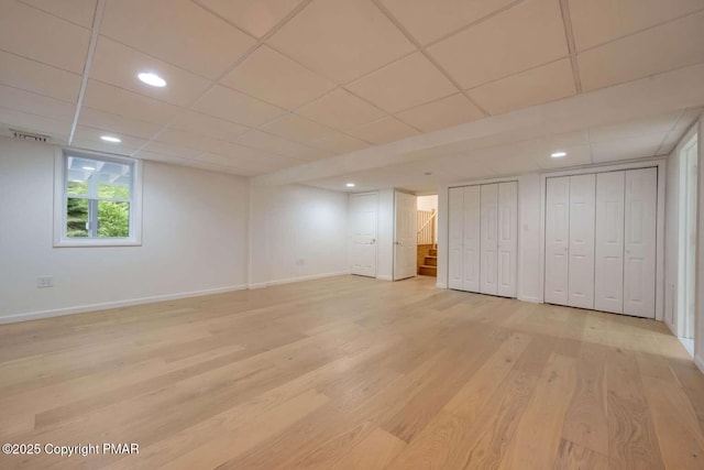 basement featuring a paneled ceiling and light wood-type flooring