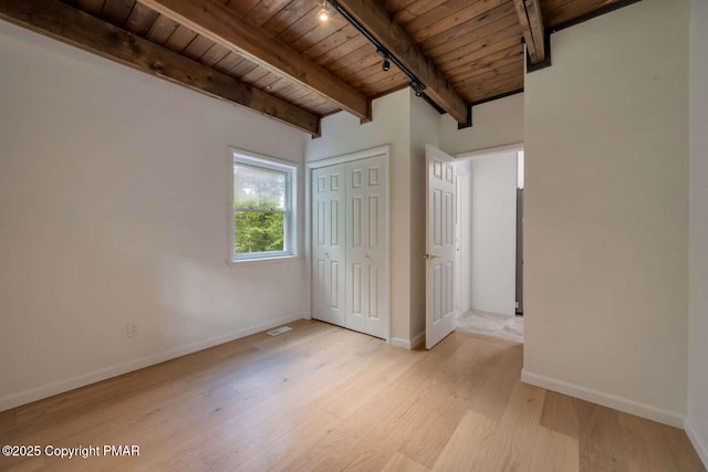 unfurnished bedroom featuring light wood-type flooring, wooden ceiling, track lighting, a closet, and beamed ceiling