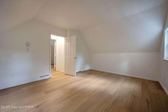 additional living space featuring vaulted ceiling and light hardwood / wood-style floors