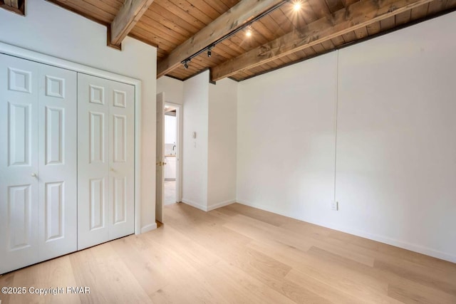 unfurnished bedroom featuring light wood-type flooring, wood ceiling, track lighting, beam ceiling, and a closet