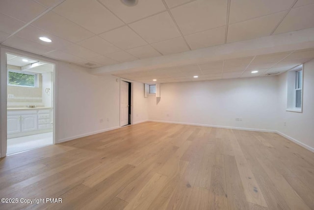 basement with a paneled ceiling and light hardwood / wood-style floors