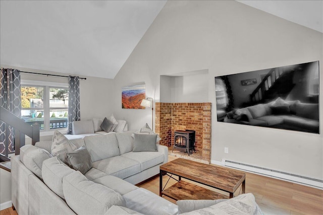 5266 Beechwood Rd, Blakeslee, PA 18610 - living area featuring a wood stove, a baseboard radiator, wood finished floors, and high vaulted ceiling