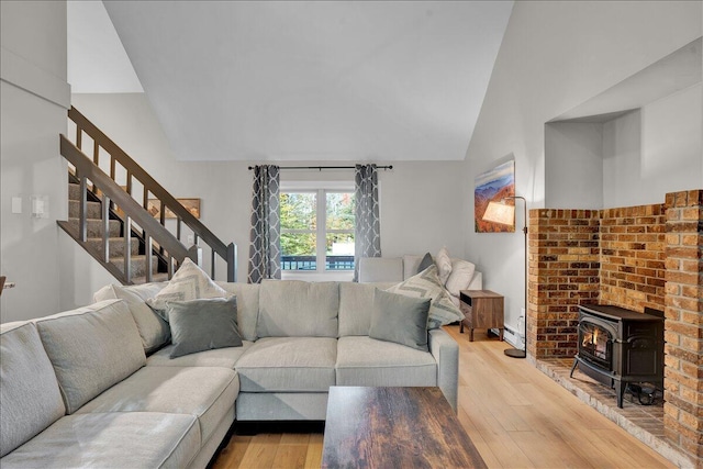 5266 Beechwood Rd, Blakeslee, PA 18610 - living area with a wood stove, light wood-type flooring, stairway, a baseboard radiator, and lofted ceiling