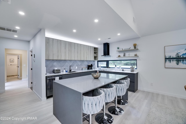 kitchen with modern cabinets, a breakfast bar area, wall chimney range hood, open shelves, and a sink