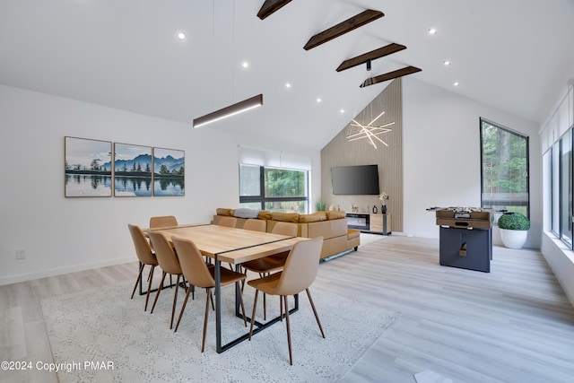 dining area with plenty of natural light, high vaulted ceiling, and light wood-style flooring