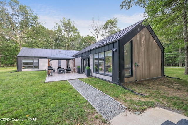 back of property featuring metal roof, a gazebo, a standing seam roof, and a lawn