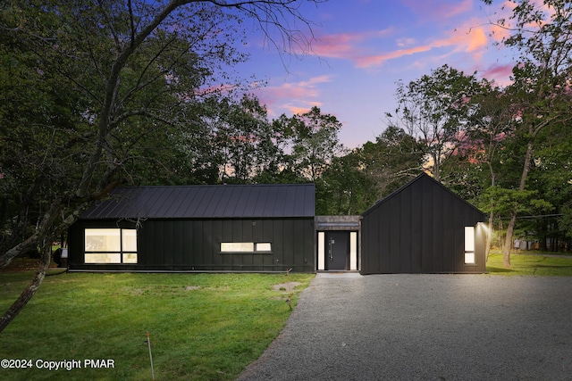 modern farmhouse with a front lawn, board and batten siding, and gravel driveway