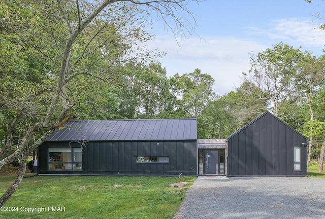 view of front of house with board and batten siding, a front yard, a standing seam roof, and metal roof