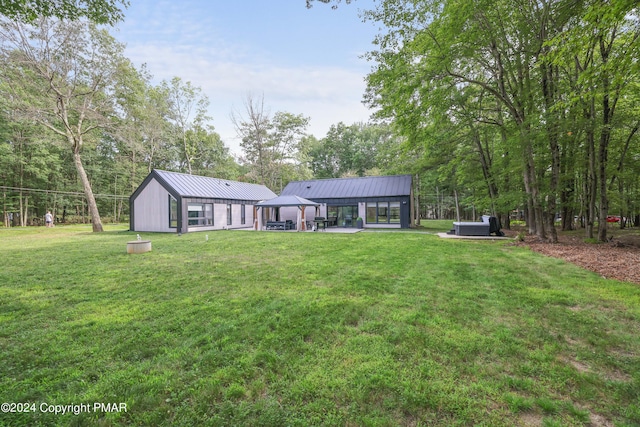 back of house with a standing seam roof, a yard, a gazebo, and metal roof