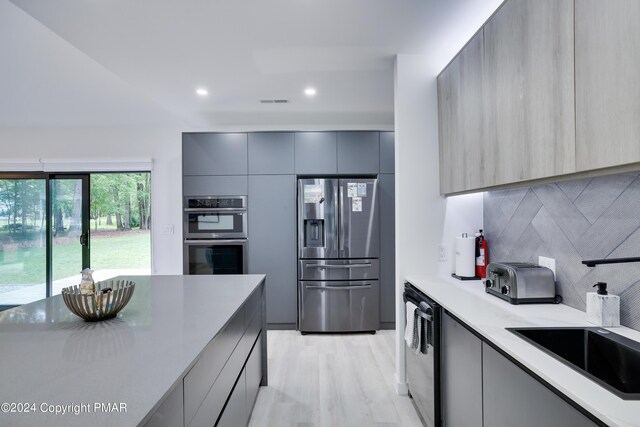 kitchen with a toaster, stainless steel appliances, light countertops, gray cabinets, and modern cabinets