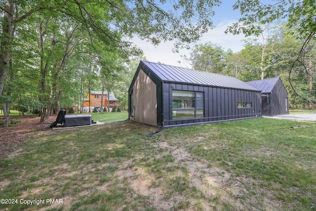 exterior space featuring board and batten siding, a standing seam roof, metal roof, and a lawn