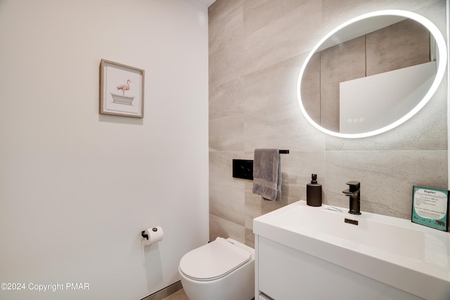 half bath with toilet, tile walls, and vanity