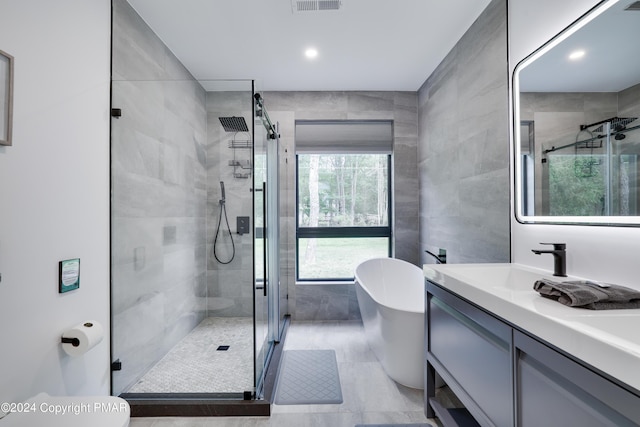 full bath with tile walls, visible vents, a freestanding bath, a stall shower, and vanity