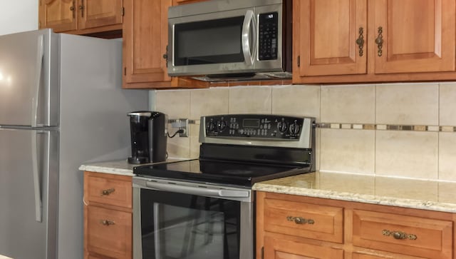 kitchen with light stone counters, decorative backsplash, and appliances with stainless steel finishes