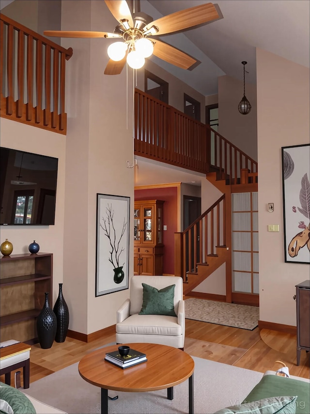 living room featuring stairway, baseboards, a high ceiling, and wood finished floors