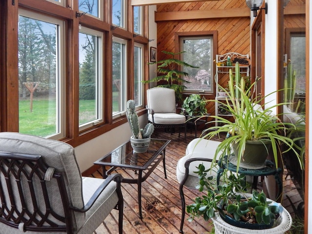 sunroom with wood-type flooring, wood walls, and plenty of natural light