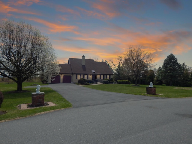 view of front of house with a garage, a yard, driveway, and a chimney