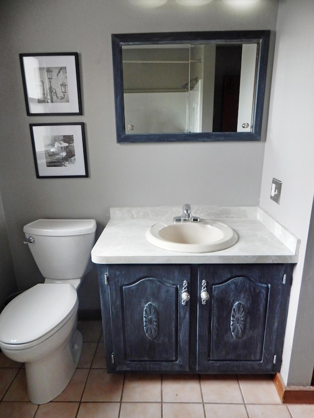 bathroom with vanity, baseboards, tile patterned flooring, and toilet