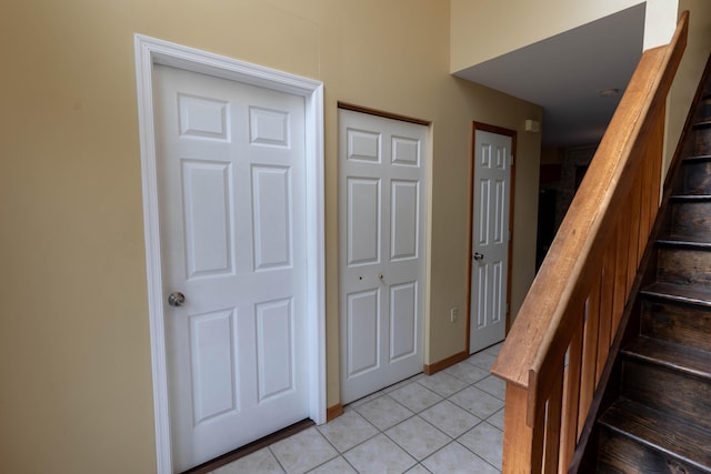 foyer featuring stairs and light tile patterned flooring