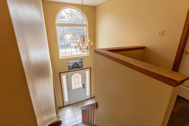 tiled entryway with a notable chandelier