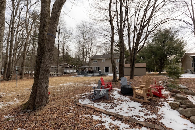 yard layered in snow with an outdoor fire pit and a deck