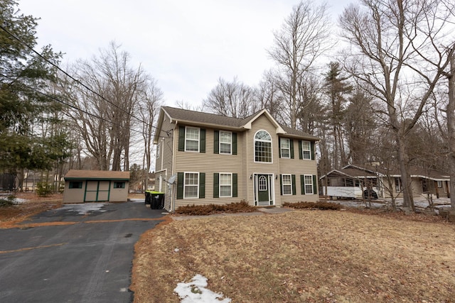 colonial-style house with driveway and an outbuilding