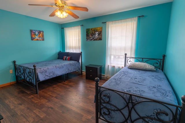 bedroom featuring a baseboard heating unit, wood finished floors, a ceiling fan, and baseboards