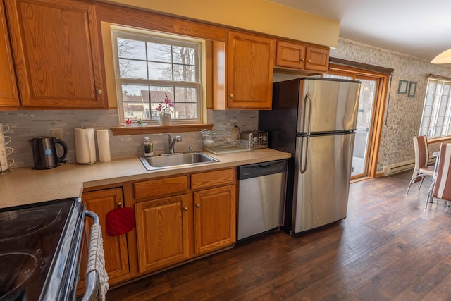 kitchen featuring brown cabinetry, appliances with stainless steel finishes, light countertops, and a sink