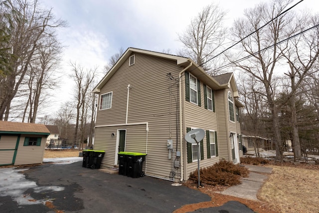 view of home's exterior featuring driveway, a storage unit, and an outdoor structure