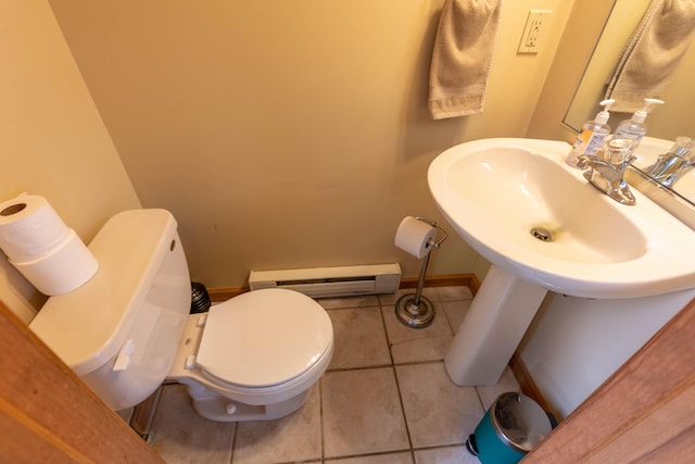 bathroom featuring toilet, baseboard heating, a sink, baseboards, and tile patterned floors