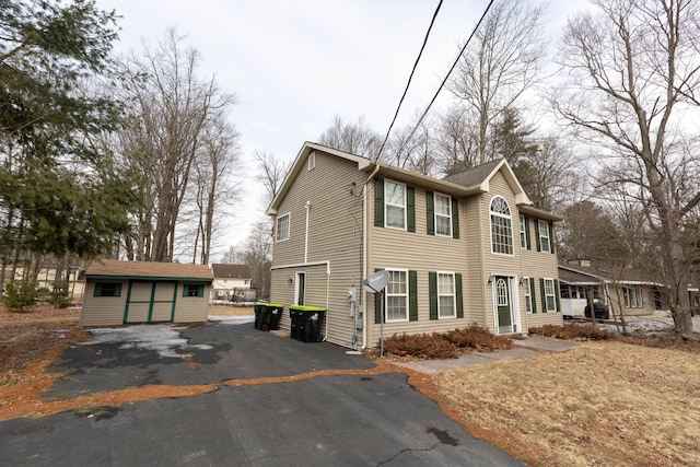 view of front facade with aphalt driveway and an outdoor structure