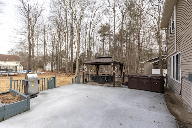 view of patio featuring a trampoline, area for grilling, a hot tub, and a gazebo