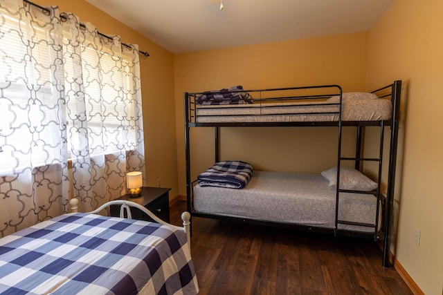 bedroom featuring multiple windows, wood finished floors, and baseboards