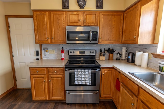 kitchen featuring a sink, stainless steel appliances, light countertops, and dark wood-style floors