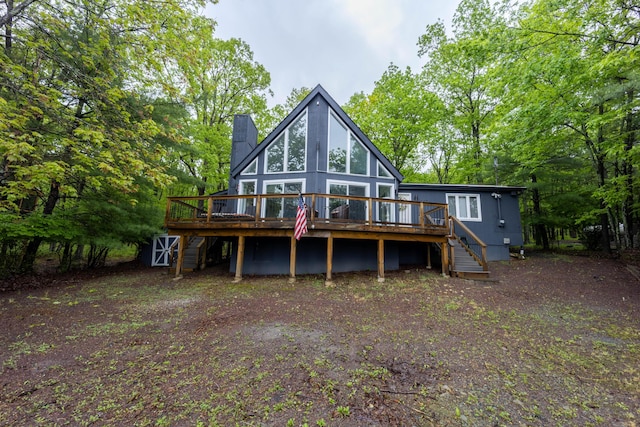 back of house with stairs, a wooden deck, and a chimney