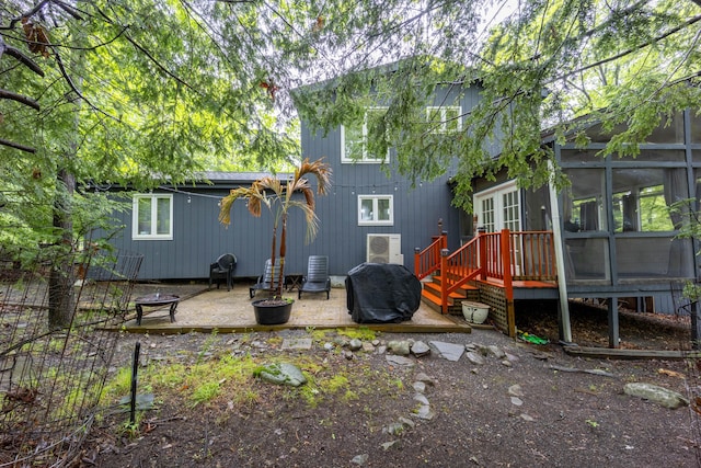 rear view of house featuring a sunroom, a wooden deck, and a patio