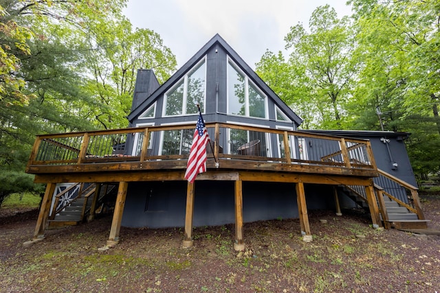 rear view of house with stairway, a wooden deck, and a chimney