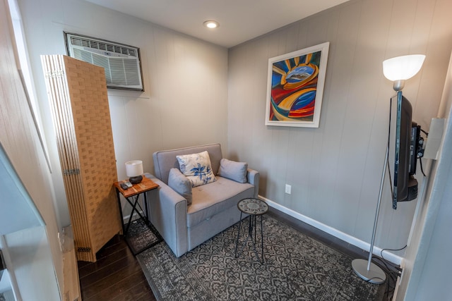 sitting room featuring wood finished floors and an AC wall unit