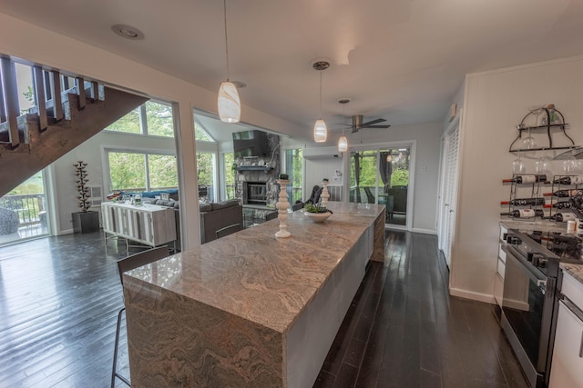 kitchen featuring stainless steel electric range, open floor plan, a fireplace, and dark wood-style floors