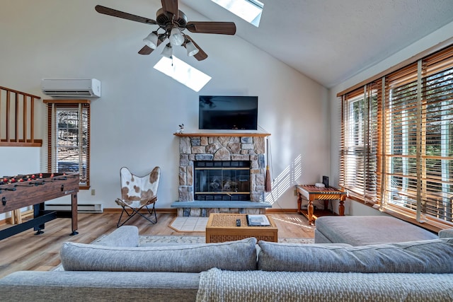 living area featuring a wall unit AC, a stone fireplace, a skylight, wood finished floors, and a ceiling fan