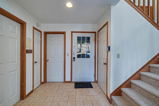 foyer with light tile patterned floors, stairs, and baseboards