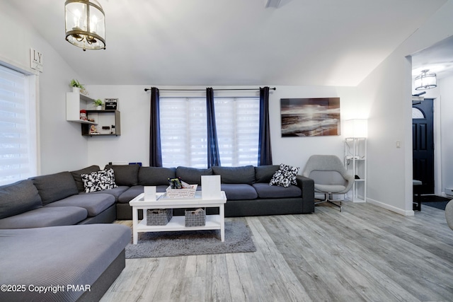 living room featuring lofted ceiling, baseboards, wood finished floors, and an inviting chandelier