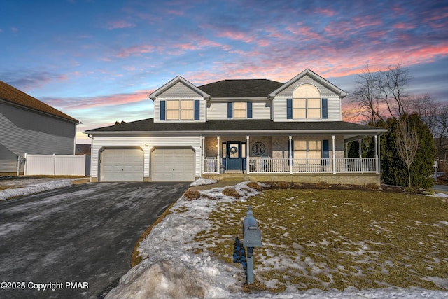 view of front facade featuring a garage, a porch, and aphalt driveway