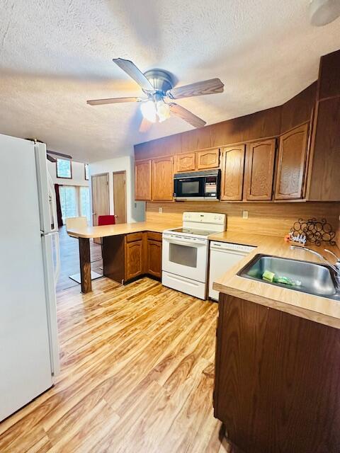 2383 Eagle Path, Bushkill, PA 18324 - kitchen with white appliances, a textured ceiling, a peninsula, light countertops, and light wood finished floors