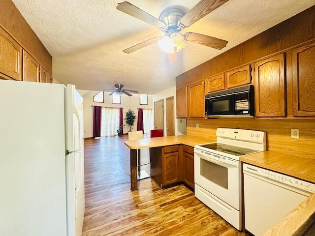 2383 Eagle Path, Bushkill, PA 18324 - kitchen featuring white appliances, ceiling fan, light wood finished floors, a peninsula, and a textured ceiling