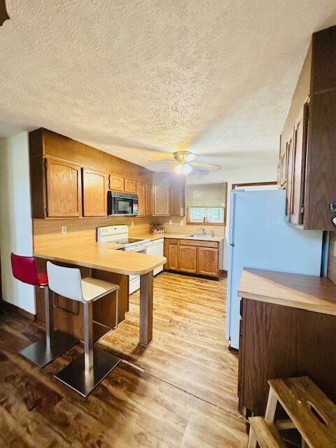 2383 Eagle Path, Bushkill, PA 18324 - kitchen featuring white appliances, a peninsula, light countertops, a textured ceiling, and light wood-style flooring